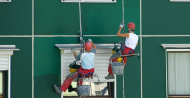 dois trabalhadores em uma corda de segurança realizando o serviço de pintura em fachadas